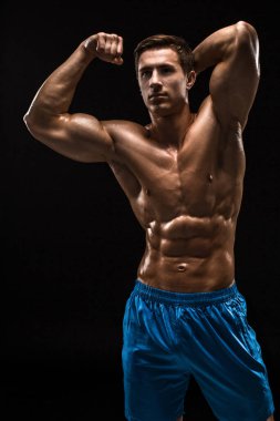 Kas ve uygun genç vücut geliştirmeci fitness erkek modeli siyah arka plan üzerinde poz. Siyah arka planda stüdyo çekimi.