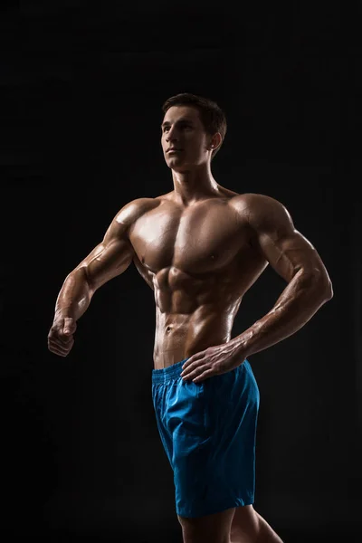 筋肉とフィット若いボディビルダーフィットネス男性モデル黒の背景の上にポーズ 黒い背景にスタジオショット — ストック写真
