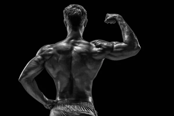 強いアスレチックマンフィットネスモデルは 背中の筋肉をポーズ 黒の背景にトリップ 黒を背景に撮影したスタジオ — ストック写真