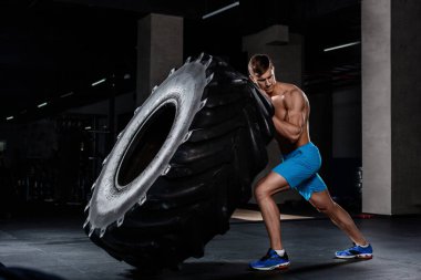 CrossFit eğitim - lastik spor salonunda saygısız adam. Kaslı bir adam büyük bir lastik iter