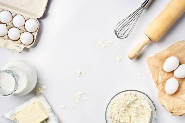 Hamur hazırlığı. Tarifteki malzemelerin miktarının ölçümü. Hamur için malzemeler: un, yumurta, merdane, çırpı, süt, tereyağı, krema. Üst görünüm, metin için boşluk. Devam et
