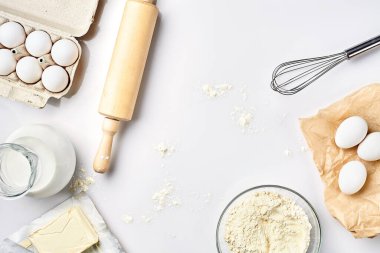 Hamur hazırlığı. Tarifteki malzemelerin miktarının ölçümü. Hamur için malzemeler: un, yumurta, merdane, çırpı, süt, tereyağı, krema. Üst görünüm, metin için boşluk. Devam et
