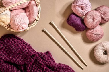 İplik topları. Hasır bir çanakta renkli iplik yumakları. Bej arka planda örgü örmek için iplik. Örgü örmek bir çeşit dikiş işidir. Örgü iğneleri ve çok renkli iplikler parlak görünüyor. Üst Manzara. Durgun hayat