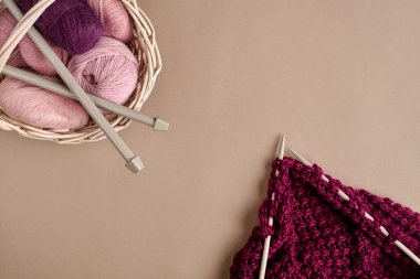 İplik topları. Hasır bir çanakta renkli iplik yumakları. Bej arka planda örgü örmek için iplik. Örgü örmek bir çeşit dikiş işidir. Örgü iğneleri ve çok renkli iplikler parlak görünüyor. Üst Manzara. Durgun hayat