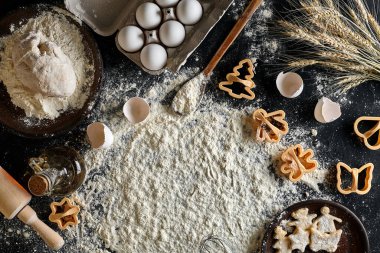 Kurabiye yapma süreci. Kurabiye, tereyağı, yumurta, yemek malzemeleri, siyah bir masada un için hamur pişirmek. Fotokopi alanı, menü, tarif ya da aşçılık dersleri için üst görünüm. Pişirme