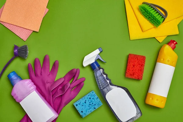 Modern deterjanlar ve temizlik aksesuarları, örneğin: renkli süngerler, dezenfektan, boş etiketli bulaşıklar için sprey ve temizleyici, iki fırça, mor lastik eldiven ve yeşil bir bulaşık bezi