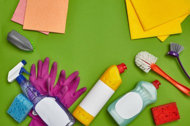 Profesyonel deterjanlar ve temizlik aksesuarları, örneğin: boş etiketli bulaşıklar için sprey, sprey ve temizleyici, fırçalar, mor lastik eldivenler ve yeşil renkli bulaşık bezleri.