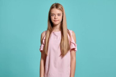 Mavi arka planda pembe tişörtlü zarif sarışın bir gencin çeşitli pozlarda stüdyo portresi. Kameranın önünde farklı duyguları ifade ediyor. Gülümsüyor ve tatmin olmuş görünüyor.