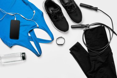 Spor, fitness, sağlıklı yaşam tarzı, kardiyo eğitimi ve nesne konsepti - kadın spor kıyafetlerine yakın çekim, beyaz arka planda ip atlama ve şişe seti. Düz yatıyordu. Üst Manzara. Boşluğu kopyala