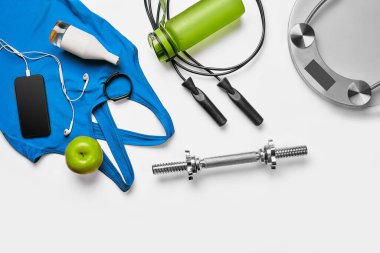 Sport, fitness, healthy lifestyle, cardio training and objects concept - close up of female sports clothing, skipping rope and bottle set on white background. Flat lay. Top view. Copy space