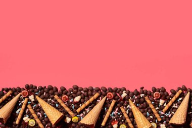 Hocolate badem ve gözleme koniler fotoğrafı mercan arka plan üzerinde büyüleyici sırayla resim altına yerleştirilir, yukarıdan görüntüleyin. Yat, yukarı alay