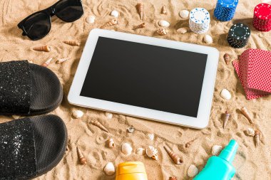Online poker oyunu ile dijital tablet ve fiş destesi şeklinde sahilde. Üstten Görünüm. Uzay kopyalayın. Düz yatıyordu