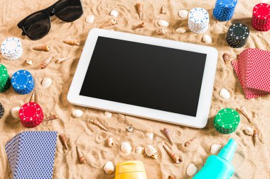 Online poker oyunu ile dijital tablet ve fiş destesi şeklinde sahilde. Üstten Görünüm. Uzay kopyalayın. Düz yatıyordu