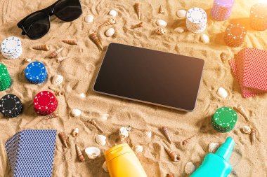 Tatil kavramı - beyaz kum deniz kabuklarını, renkli poker fişleri ve kartları ile kumar. Üstten Görünüm. Uzay kopyalayın. Yaz. Güneş parlaması