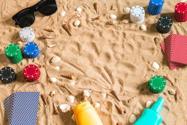 Tatil kavramı - beyaz kum deniz kabuklarını, renkli poker fişleri ve kartları ile kumar. Üstten Görünüm. Uzay kopyalayın. Yaz