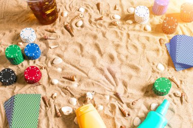 Tatil kavramı - beyaz kum deniz kabuklarını, renkli poker fişleri ve kartları ile kumar. Üstten Görünüm. Uzay kopyalayın. Yaz. Güneş parlaması