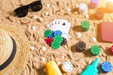Plaj pokeri. Çipler ve kartlar kumsalda. Deniz kabuklarının, güneş gözlüklerinin ve şapkanın etrafında. Üst Manzara. Uzayı kopyala Düz yatıyordu. Güneş parlaması