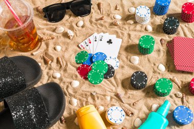 Plaj pokeri. Çipler ve kartlar kumsalda. Deniz kabuklarının, güneş gözlüklerinin ve parmak arası terliklerin etrafında. Üst Manzara. Uzayı kopyala Düz yatıyordu