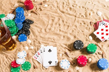 Tatil kavramı - beyaz kum deniz kabuklarını, renkli poker fişleri ve kartları ile kumar. Üstten Görünüm. Uzay kopyalayın. Yaz
