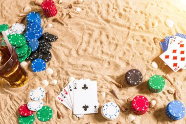 Tatil kavramı - beyaz kum deniz kabuklarını, renkli poker fişleri ve kartları ile kumar. Üstten Görünüm. Uzay kopyalayın. Yaz. Güneş parlaması