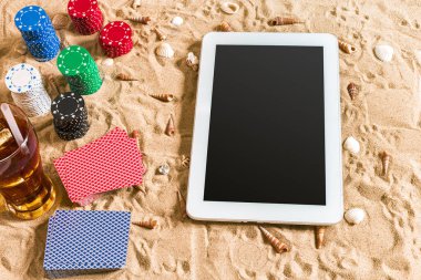 Online poker oyunu ile dijital tablet ve fiş destesi şeklinde sahilde. Üstten Görünüm. Uzay kopyalayın. Düz yatıyordu