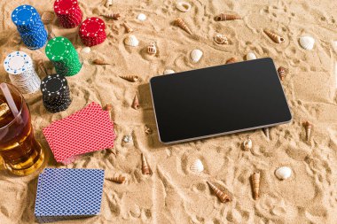 Online poker oyunu ile dijital tablet ve fiş destesi şeklinde sahilde. Üstten Görünüm. Uzay kopyalayın. Düz yatıyordu