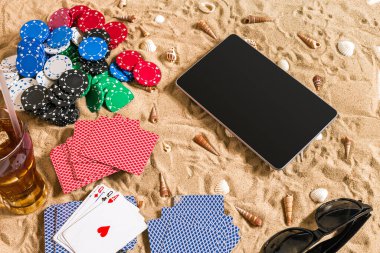 Tatil kavramı - beyaz kum deniz kabuklarını, renkli poker fişleri ve kartları ile kumar. Üstten Görünüm. Uzay kopyalayın. Yaz