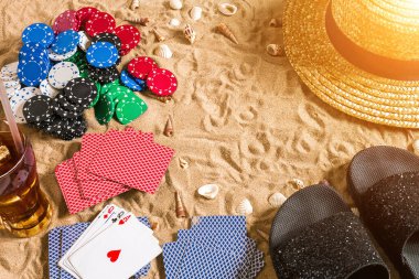 Plaj pokeri. Çipler ve kartlar kumsalda. Deniz kabukları, şapkalar ve parmak arası terlikler. Üst Manzara. Uzayı kopyala Düz yatıyordu. Güneş parlaması