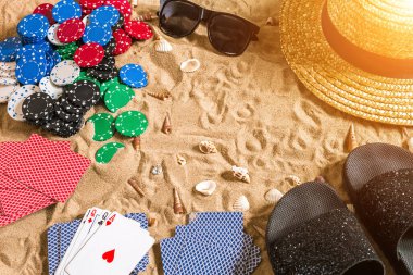Plaj pokeri. Çipler ve kartlar kumsalda. Deniz kabuklarının, güneş gözlüklerinin ve parmak arası terliklerin etrafında. Üst Manzara. Uzayı kopyala Düz yatıyordu. Güneş parlaması