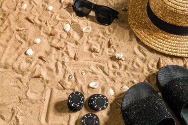Beachpoker. Chips on the sand. Around the seashells, sunglasses and flip flops. Top view. Copy space. Flat lay