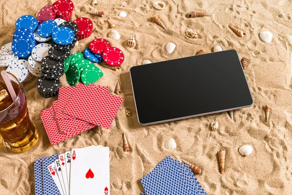 Online poker game on the beach with digital tablet and stacks of chips. Top view. Copy space. Flat lay