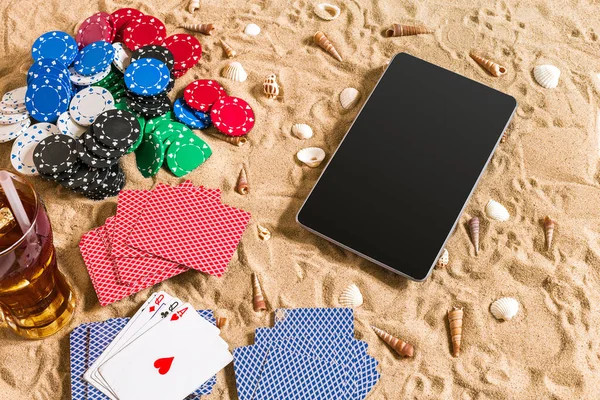 Online poker game on the beach with digital tablet and stacks of chips. Top view. Copy space. Flat lay