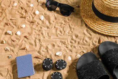 Beachpoker. Chips and cards on the sand. Around the seashells, sunglasses and flip flops. Top view. Copy space. Flat lay