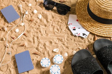 Plaj pokeri. Çipler ve kartlar kumsalda. Deniz kabuklarının, güneş gözlüklerinin ve parmak arası terliklerin etrafında. Üst Manzara. Uzayı kopyala Düz yatıyordu