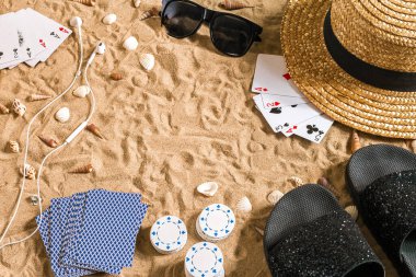 Plaj pokeri. Çipler ve kartlar kumsalda. Deniz kabuklarının, güneş gözlüklerinin ve parmak arası terliklerin etrafında. Üst Manzara. Uzayı kopyala Düz yatıyordu