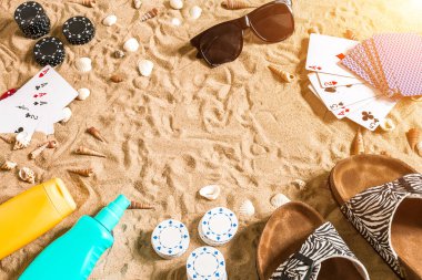 Plaj pokeri. Çipler ve kartlar kumsalda. Deniz kabuklarının, güneş gözlüklerinin ve parmak arası terliklerin etrafında. Üst Manzara. Uzayı kopyala Düz yatıyordu. Güneş parlaması