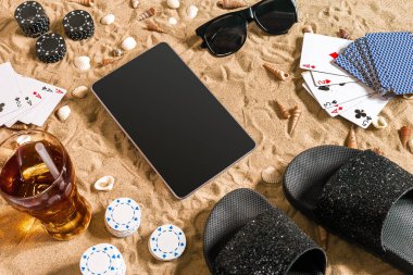 Online poker oyunu ile dijital tablet ve fiş destesi şeklinde sahilde. Üstten Görünüm. Uzay kopyalayın. Düz yatıyordu