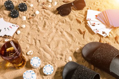 Plaj pokeri. Çipler ve kartlar kumsalda. Deniz kabuklarının, güneş gözlüklerinin ve parmak arası terliklerin etrafında. Üst Manzara. Uzayı kopyala Düz yatıyordu. Güneş parlaması