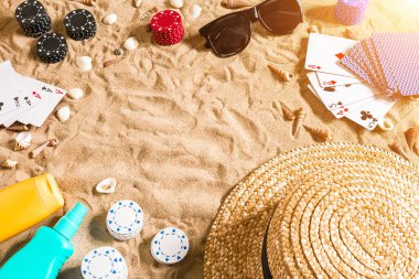 Plaj pokeri. Çipler ve kartlar kumsalda. Deniz kabuklarının, güneş gözlüklerinin ve şapkanın etrafında. Üst Manzara. Uzayı kopyala Düz yatıyordu. Güneş parlaması