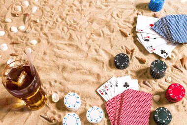 Plaj pokeri. Çipler ve kartlar kumsalda. Deniz kabukları ve soğuk bir bardakta içki. Üst Manzara. Uzayı kopyala Düz yatıyordu