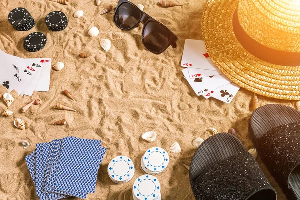 Plaj pokeri. Çipler ve kartlar kumsalda. Deniz kabuklarının, güneş gözlüklerinin ve parmak arası terliklerin etrafında. Üst Manzara. Uzayı kopyala Düz yatıyordu. Güneş parlaması