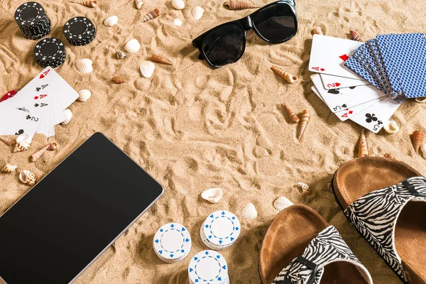 Online poker game on the beach with digital tablet and stacks of chips. Top view. Copy space. Flat lay