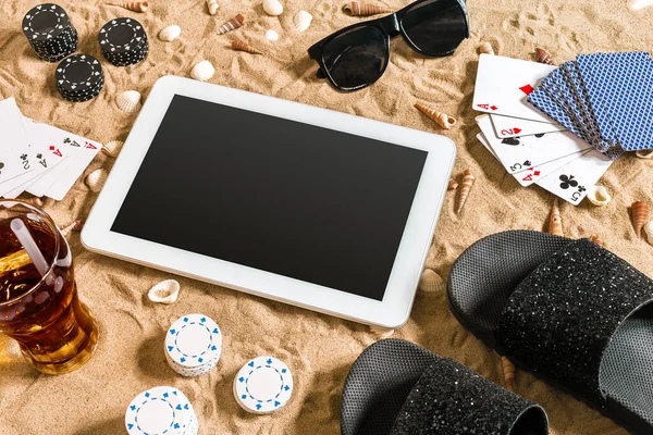 Online poker game on the beach with digital tablet and stacks of chips. Top view. Copy space. Flat lay