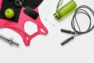 Sport, fitness, healthy lifestyle, cardio training and objects concept - close up of female sports clothing, skipping rope and bottle set on white background. Flat lay. Top view. Copy space