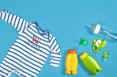 Baby care with bath set. Nipple, toy, clothes, shampoo on blue background top view mockup. Flat lay. Still life. Copy space
