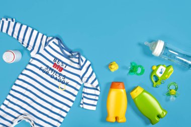 Baby care with bath set. Nipple, toy, clothes, shampoo on blue background top view mockup. Flat lay. Still life. Copy space