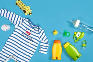 Baby care with bath set. Nipple, toy, clothes, shampoo on blue background top view mockup. Flat lay. Still life. Copy space