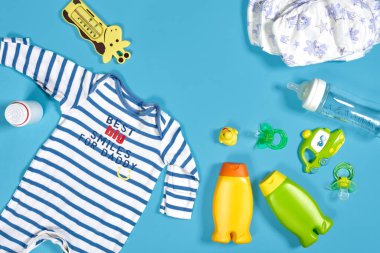 Baby care with bath set. Nipple, toy, clothes, shampoo on blue background top view mockup. Flat lay. Still life. Copy space