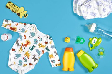 Banyo takımlı bebek bakımı. Meme ucu, oyuncak, kıyafetler, mavi arka planda şampuan. Düz yatıyordu. Durgun hayat. Boşluğu kopyala