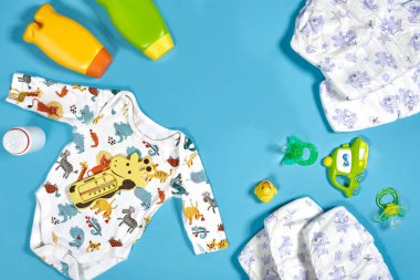 Banyo takımlı bebek bakımı. Meme ucu, oyuncak, kıyafetler, mavi arka planda şampuan. Düz yatıyordu. Durgun hayat. Boşluğu kopyala